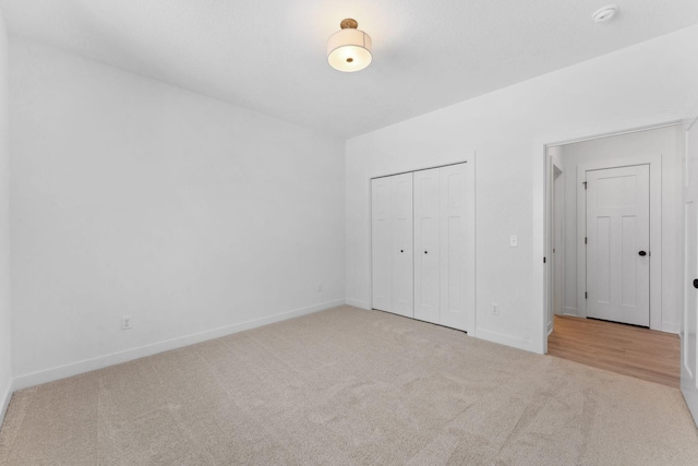 unfurnished bedroom featuring light carpet and a closet