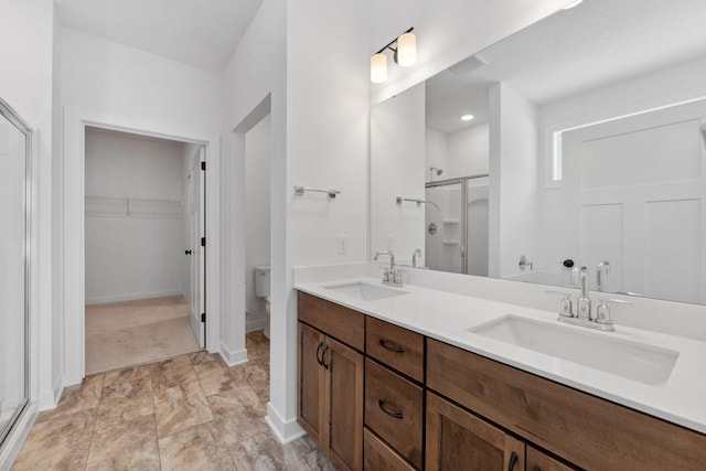 bathroom with toilet, vanity, and a shower with shower door