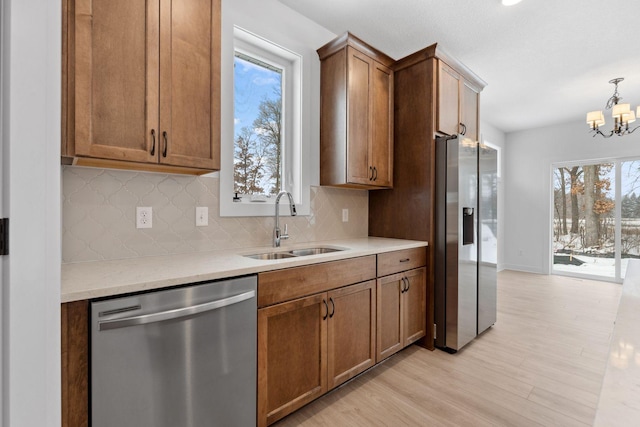 kitchen featuring sink, appliances with stainless steel finishes, decorative backsplash, decorative light fixtures, and light wood-type flooring