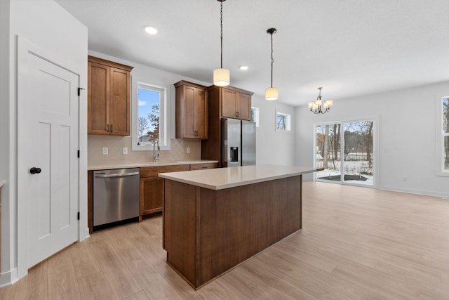 kitchen featuring a kitchen island, appliances with stainless steel finishes, pendant lighting, sink, and light wood-type flooring