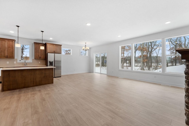 kitchen featuring stainless steel fridge, tasteful backsplash, a notable chandelier, decorative light fixtures, and light wood-type flooring