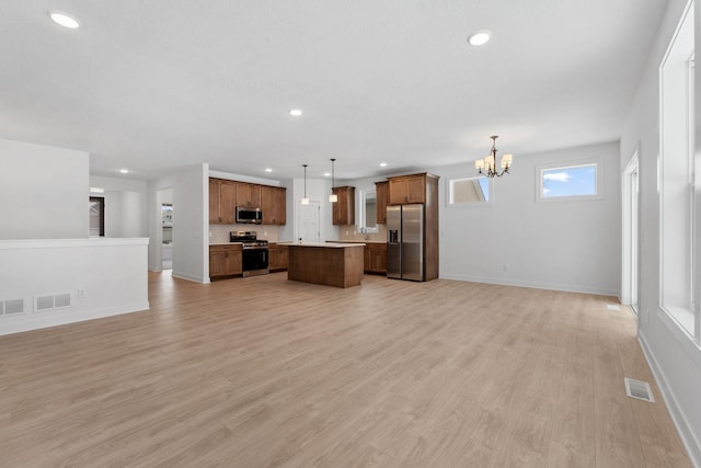 unfurnished living room featuring an inviting chandelier and light hardwood / wood-style flooring