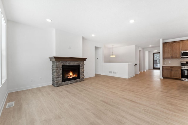 unfurnished living room featuring a stone fireplace and light hardwood / wood-style floors