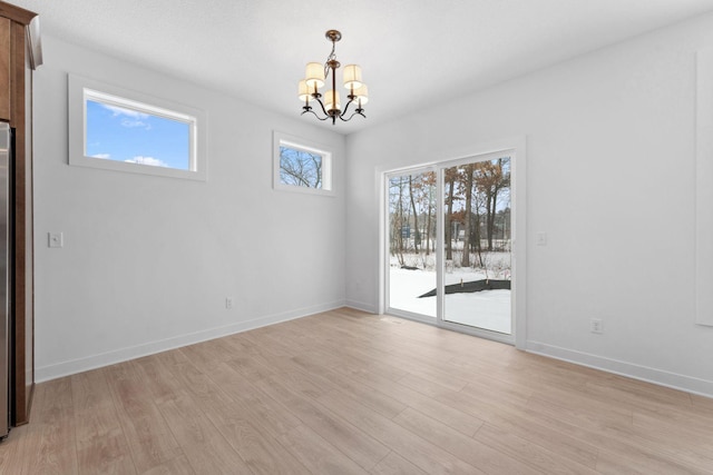 unfurnished dining area with a chandelier and light hardwood / wood-style floors