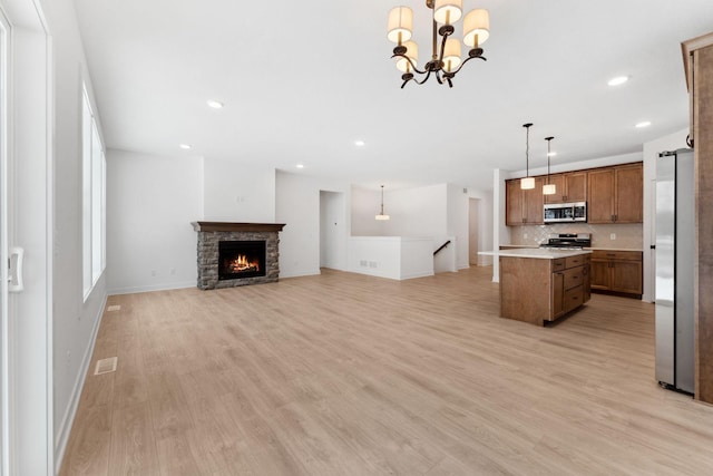 kitchen featuring stainless steel appliances, a kitchen island, pendant lighting, and light hardwood / wood-style flooring