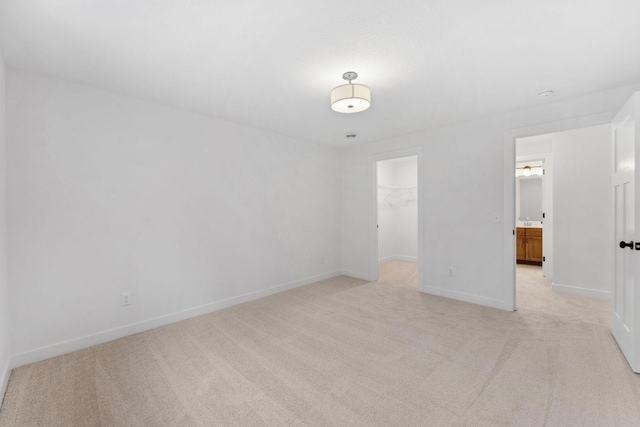 unfurnished bedroom featuring a walk in closet, a closet, and light carpet