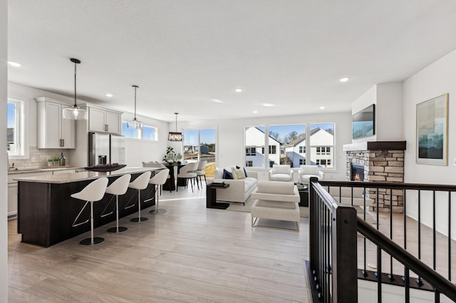 living room with a stone fireplace, an inviting chandelier, and light wood-type flooring