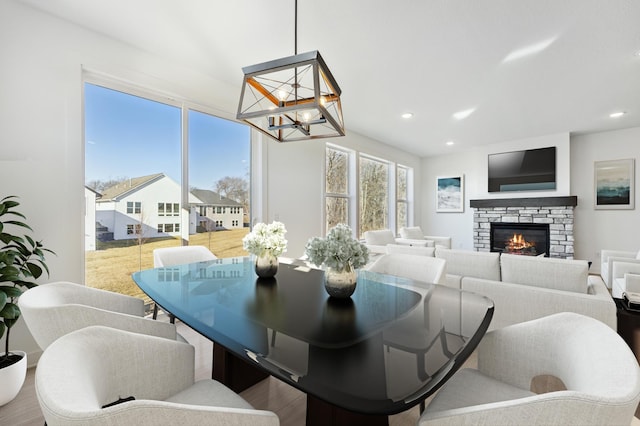 dining room with a notable chandelier, a fireplace, and hardwood / wood-style floors