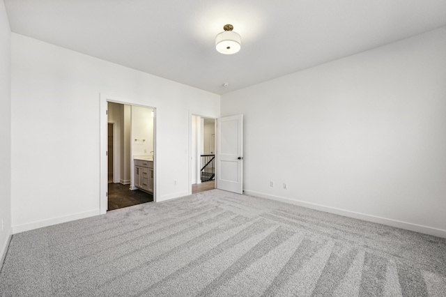 unfurnished bedroom featuring ensuite bath and dark colored carpet