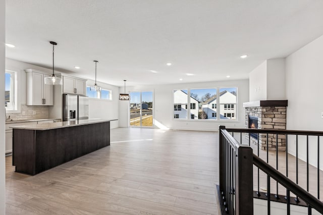 kitchen featuring light hardwood / wood-style flooring, white cabinetry, decorative light fixtures, and stainless steel fridge with ice dispenser