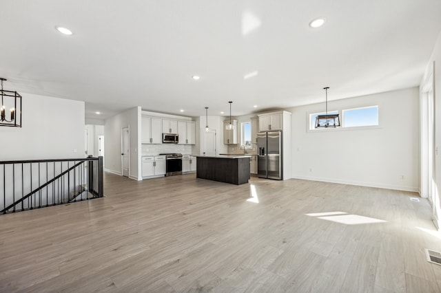 unfurnished living room with an inviting chandelier and light hardwood / wood-style flooring