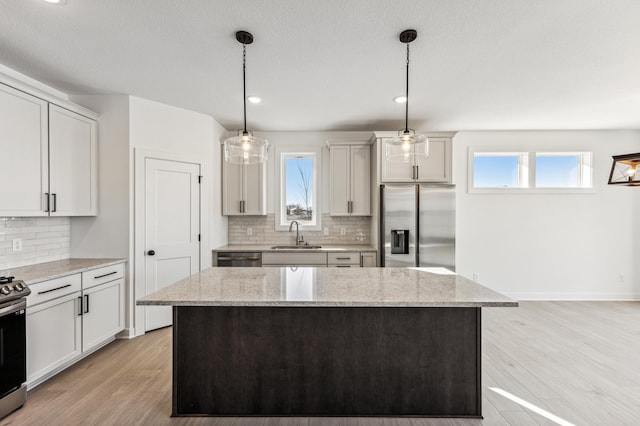 kitchen featuring a wealth of natural light, appliances with stainless steel finishes, and pendant lighting