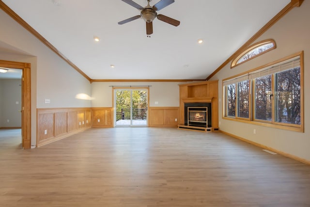 unfurnished living room featuring a large fireplace, ceiling fan, light wood-type flooring, vaulted ceiling, and ornamental molding