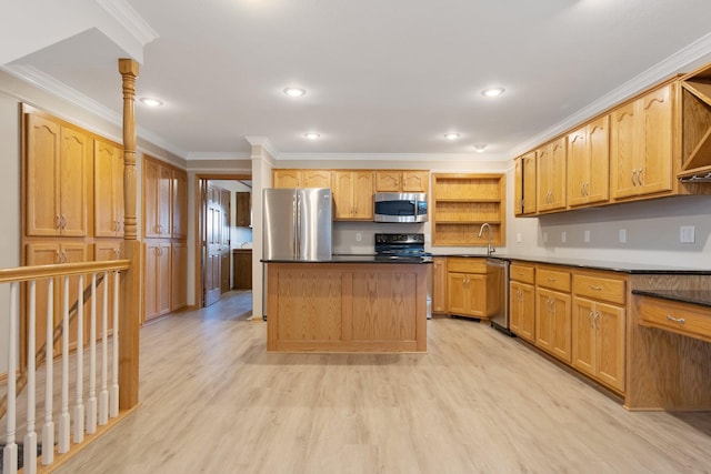 kitchen with appliances with stainless steel finishes, decorative columns, a center island, ornamental molding, and light hardwood / wood-style flooring