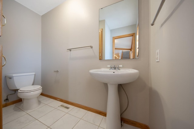 bathroom with toilet, sink, and tile patterned floors