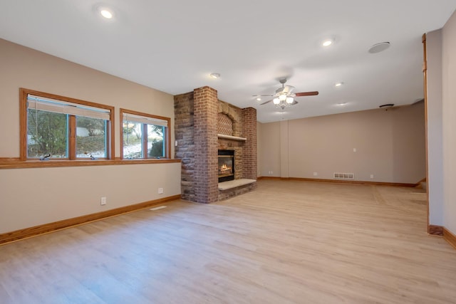 unfurnished living room with a brick fireplace, light hardwood / wood-style floors, and ceiling fan