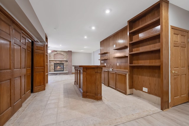 kitchen featuring sink, light wood-type flooring, a fireplace, a kitchen island, and a breakfast bar