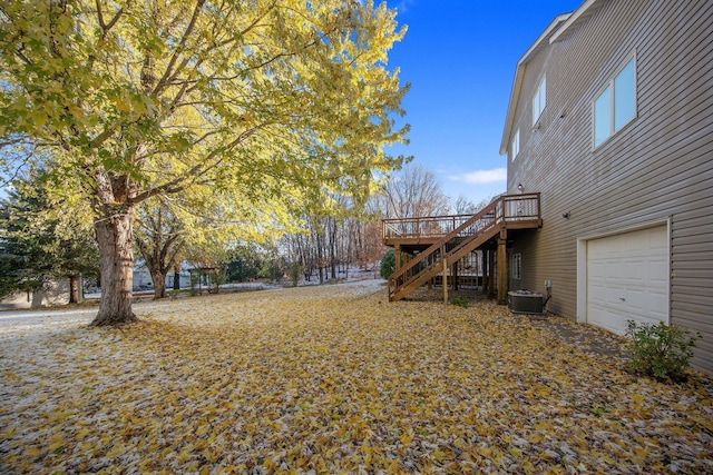 view of yard with central air condition unit, a wooden deck, and a garage