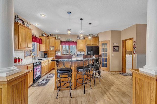 kitchen with washer / dryer, backsplash, a kitchen island, and black appliances