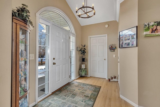 entryway with a chandelier, light hardwood / wood-style floors, and lofted ceiling