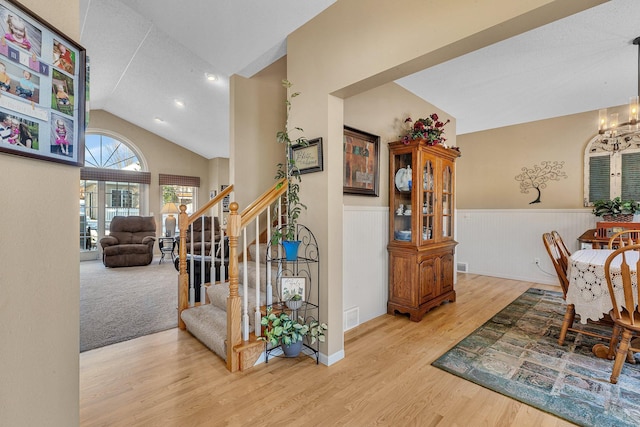 interior space with light hardwood / wood-style flooring, vaulted ceiling, and a notable chandelier