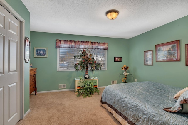 bedroom with a closet, light colored carpet, and a textured ceiling