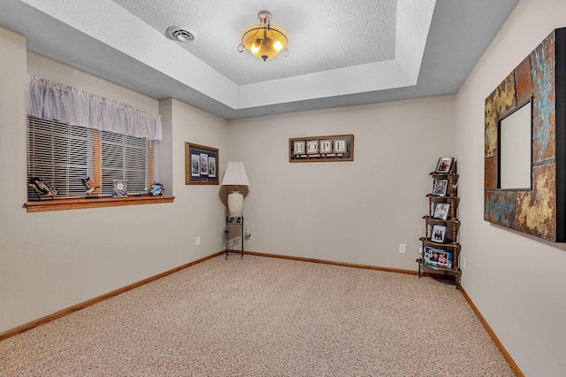 carpeted empty room featuring a textured ceiling and a tray ceiling