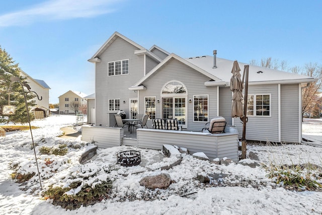 snow covered rear of property featuring a fire pit and a deck