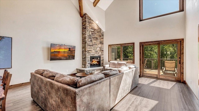 living area featuring dark wood-style floors, a fireplace, high vaulted ceiling, and baseboards