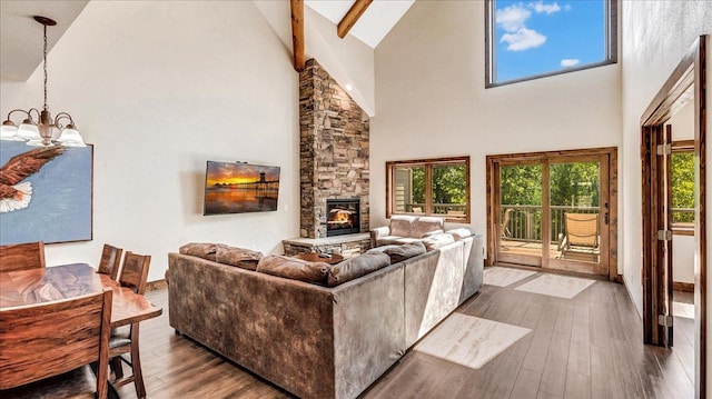 living room featuring dark wood-type flooring, a fireplace, a notable chandelier, and high vaulted ceiling