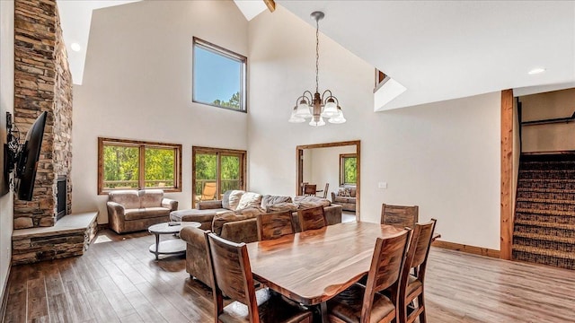 dining room with baseboards, wood finished floors, stairs, a high ceiling, and a notable chandelier