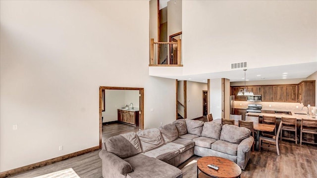 living area with baseboards, visible vents, wood finished floors, a high ceiling, and stairs