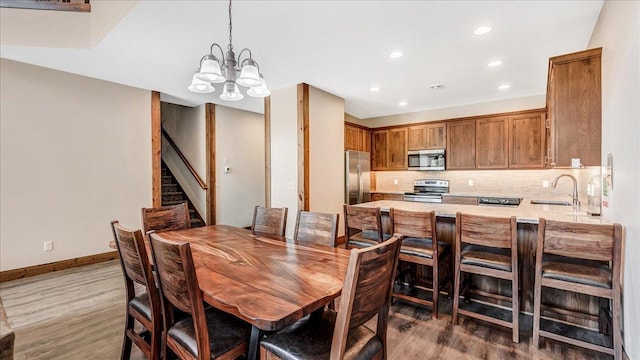 dining room with a chandelier, recessed lighting, baseboards, light wood-style floors, and stairway