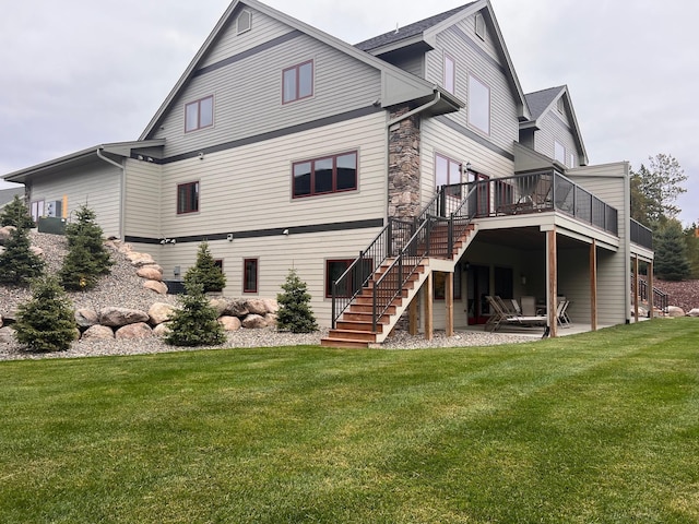 back of house featuring a lawn, stone siding, stairs, a deck, and a patio area