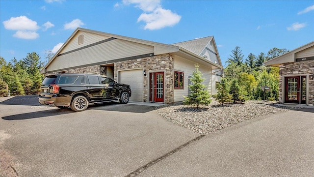 view of side of property with stone siding, aphalt driveway, and an attached garage