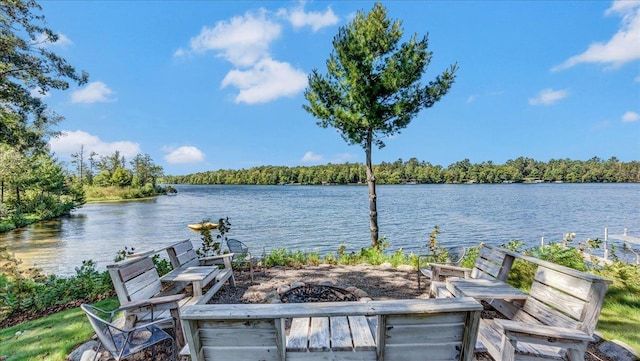 property view of water featuring a fire pit and a forest view