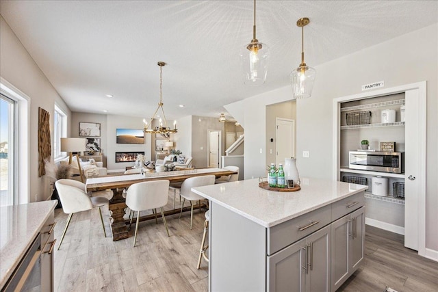 kitchen featuring a breakfast bar, light hardwood / wood-style flooring, gray cabinetry, and decorative light fixtures