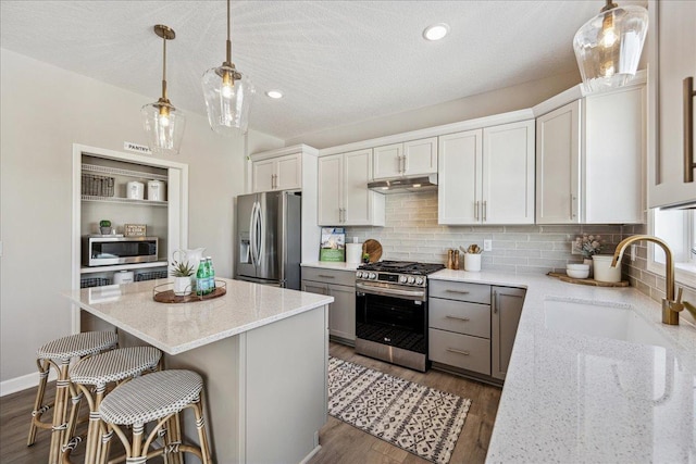 kitchen with light stone countertops, a kitchen island, white cabinets, and stainless steel appliances