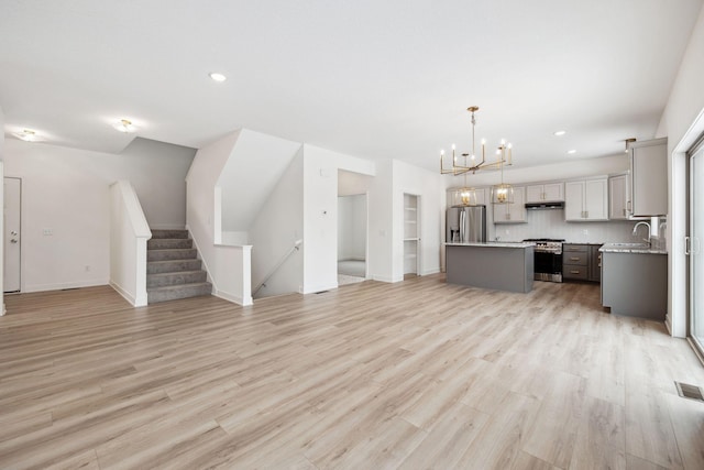 unfurnished living room featuring visible vents, recessed lighting, light wood finished floors, baseboards, and a chandelier