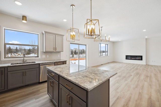 kitchen featuring a notable chandelier, gray cabinetry, a sink, decorative backsplash, and dishwasher