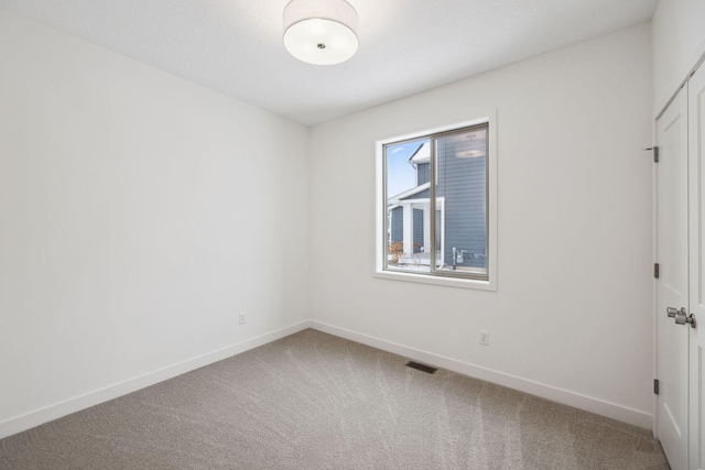 carpeted empty room featuring visible vents and baseboards