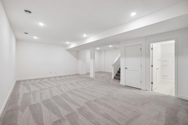 finished basement with visible vents, light carpet, recessed lighting, stairway, and baseboards