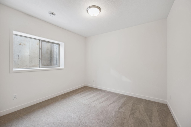 carpeted spare room with visible vents and baseboards