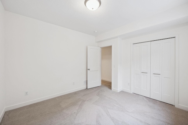 unfurnished bedroom featuring a closet, baseboards, carpet floors, and a textured ceiling