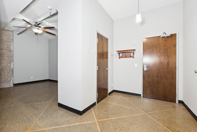 foyer entrance with ceiling fan and a high ceiling