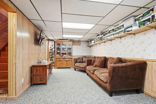 carpeted living room with a paneled ceiling and wooden walls