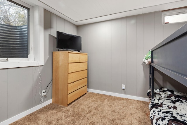 bedroom featuring wooden walls and light colored carpet