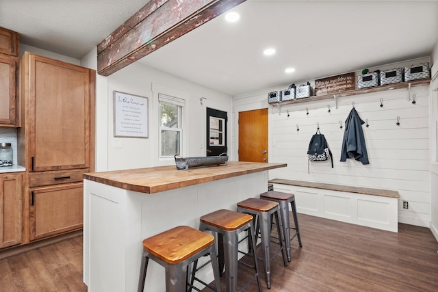 kitchen with a breakfast bar area, a kitchen island, butcher block countertops, and dark hardwood / wood-style floors