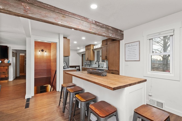 kitchen with sink, wood counters, light hardwood / wood-style flooring, and a kitchen breakfast bar