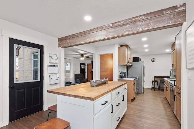 kitchen with a kitchen island, stainless steel appliances, wood counters, light wood-type flooring, and white cabinetry